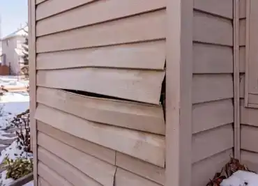 Warped and buckling siding panels on a Calgary home in need of repair or replacement