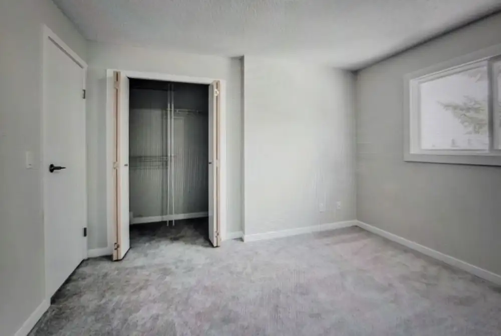 Finished basement room with painted drywall, trim, a closet and a window in a Calgary home