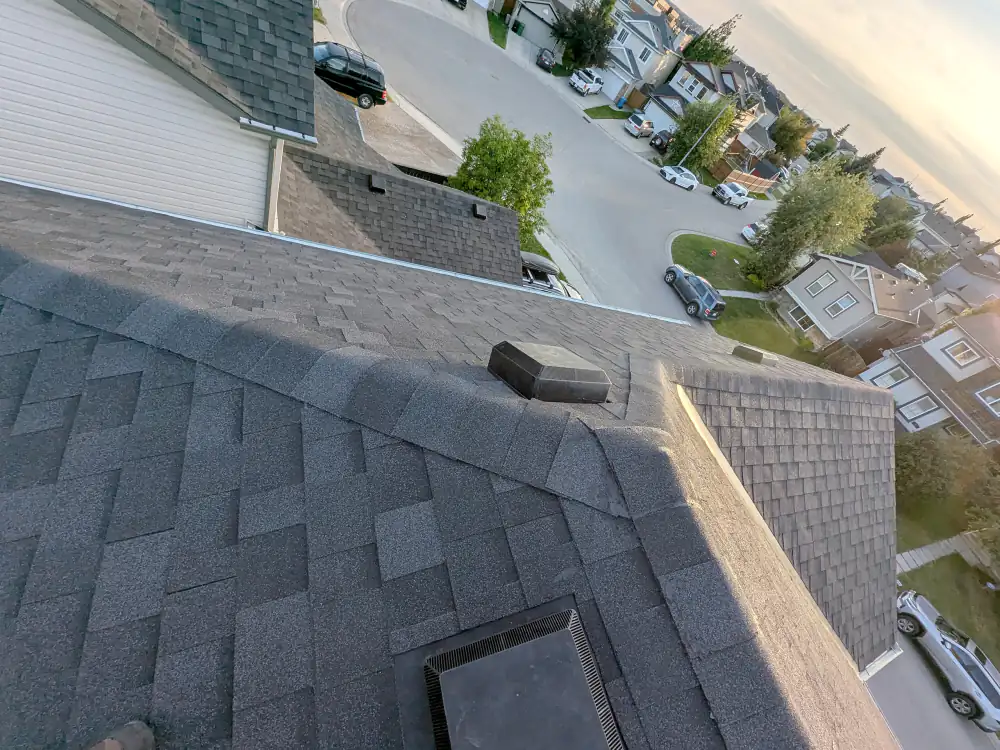 Finished asphalt shingle roof with ridge caps and roof vents after a roof replacement on a Calgary house