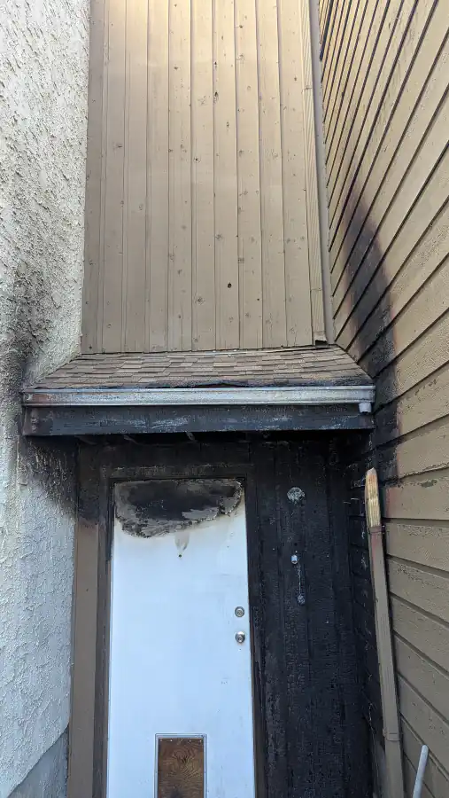 Charred entry door, wall boards and roof edge after a fire at a Calgary townhouse before repairs