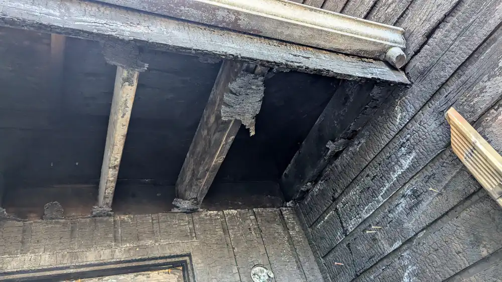 Burnt soffit, rafter tails and wall boards above an entry door after a fire at a Calgary townhouse