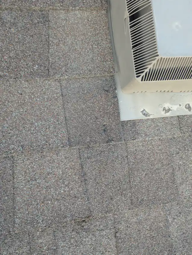 Hail marks on shingles and a dented metal roof vent on a Calgary roof during a hail damage inspection