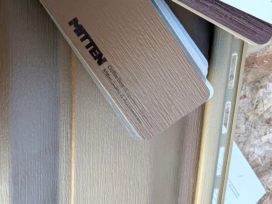 Mitten vinyl siding sample panel held against a wall to compare colour and woodgrain texture during a Calgary siding estimate