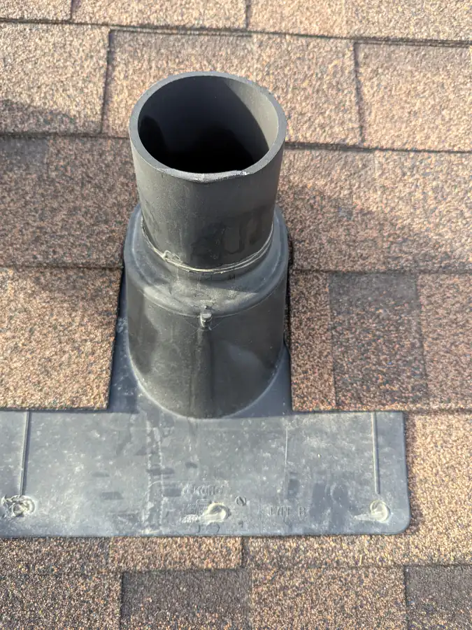 Close up of a plastic pipe boot with flashing and exposed nail heads on an asphalt shingle roof in Calgary