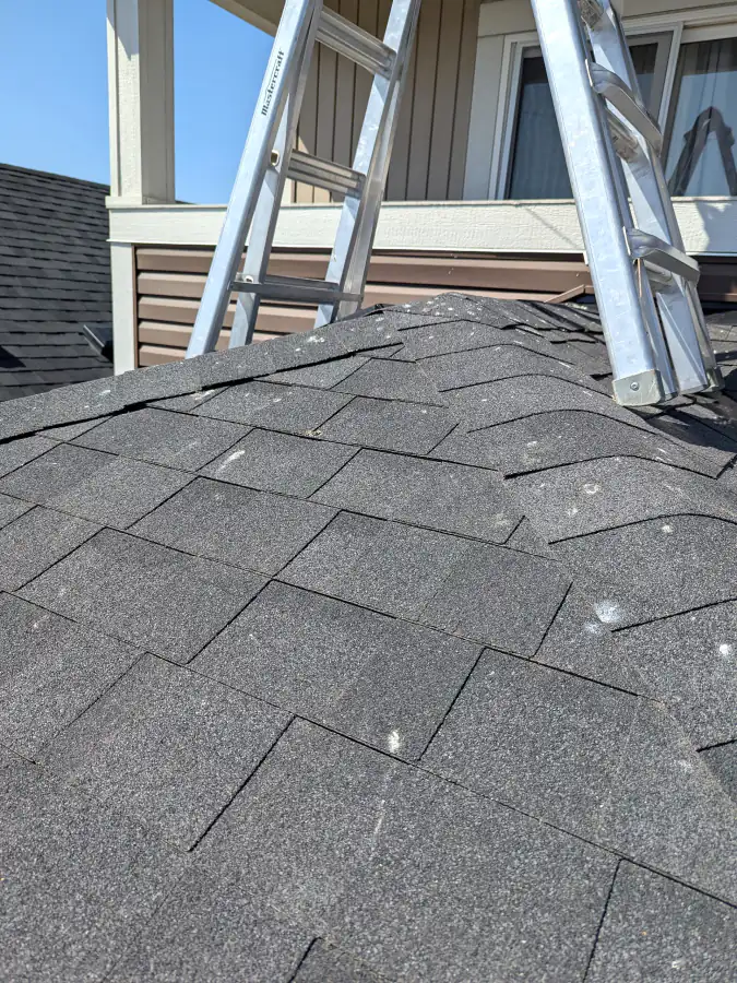 Hip and ridge shingles with exposed nail heads and worn spots on a Calgary roof that can let water in