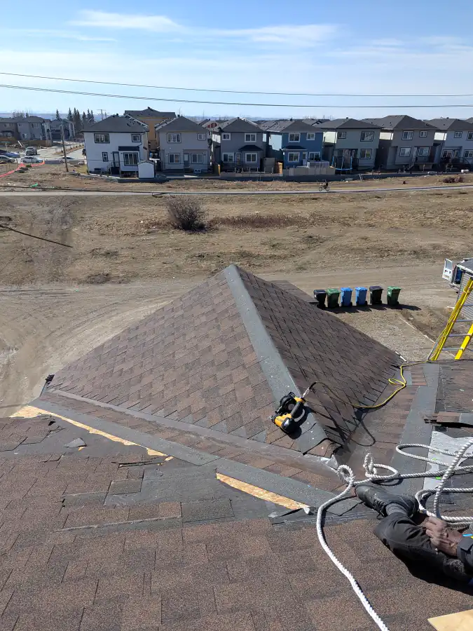 Hip and ridge shingles on a Calgary roof with a view across open land and nearby homes