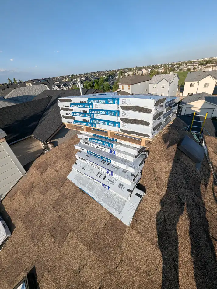 IKO Cambridge and hip and ridge shingle bundles staged on a Calgary roof before a roof replacement
