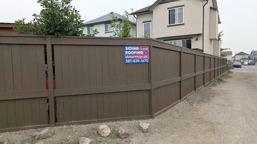 Long run of stained wood fence along a back lane in Calgary after installation