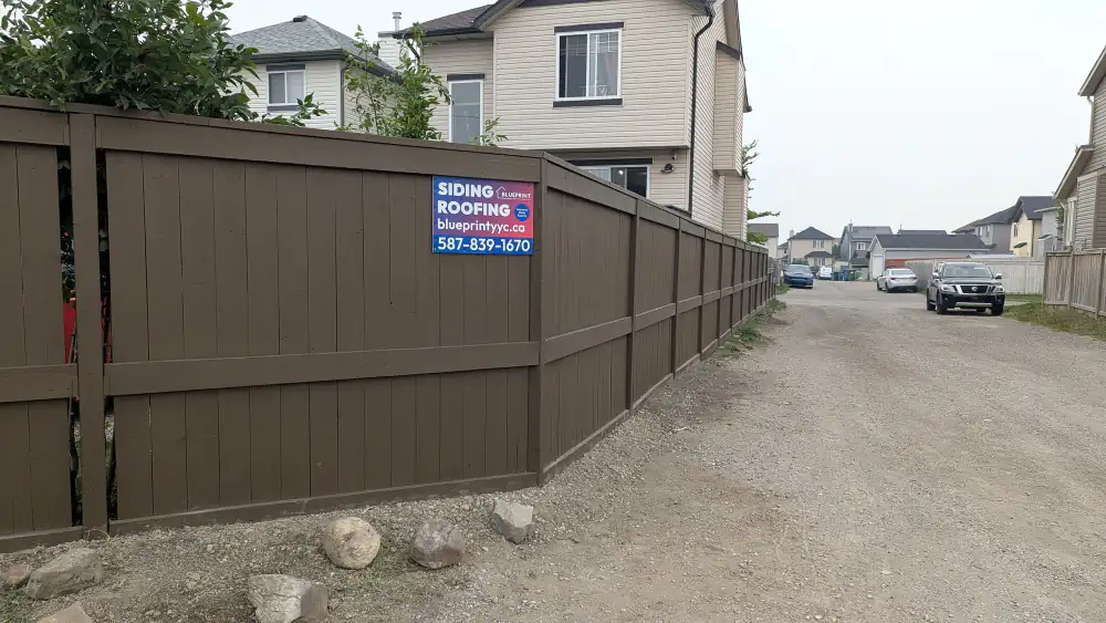 Finished stained wood privacy fence with posts and rails along a back lane in Calgary