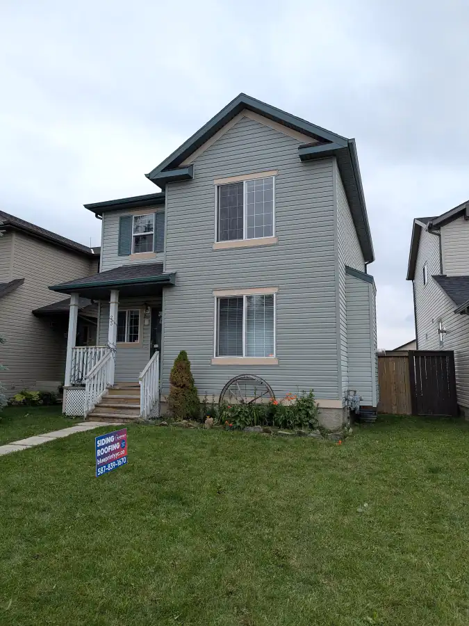Two-storey Calgary house with new grey-blue vinyl siding, trim and soffit finished by Blueprint Construction